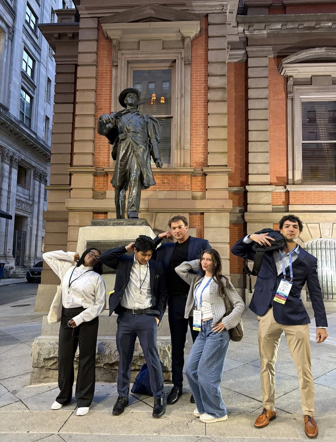 Students posing playfully in front of a bronze statue